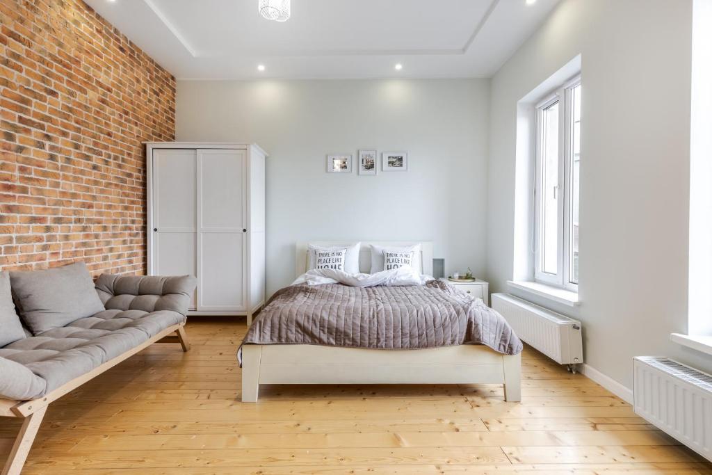 a bedroom with a bed and a couch and a brick wall at InshiApartments on Grigorenko's square in Lviv
