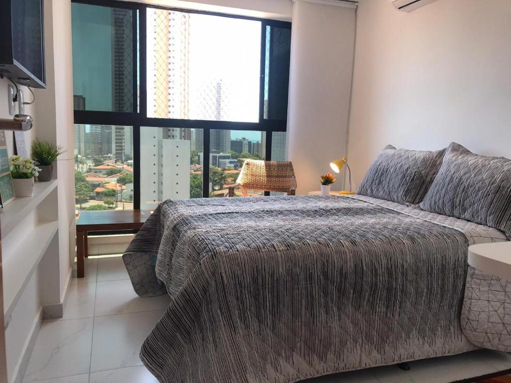 um quarto com uma cama grande e uma janela grande em Flat Novíssimo João Pessoa em João Pessoa