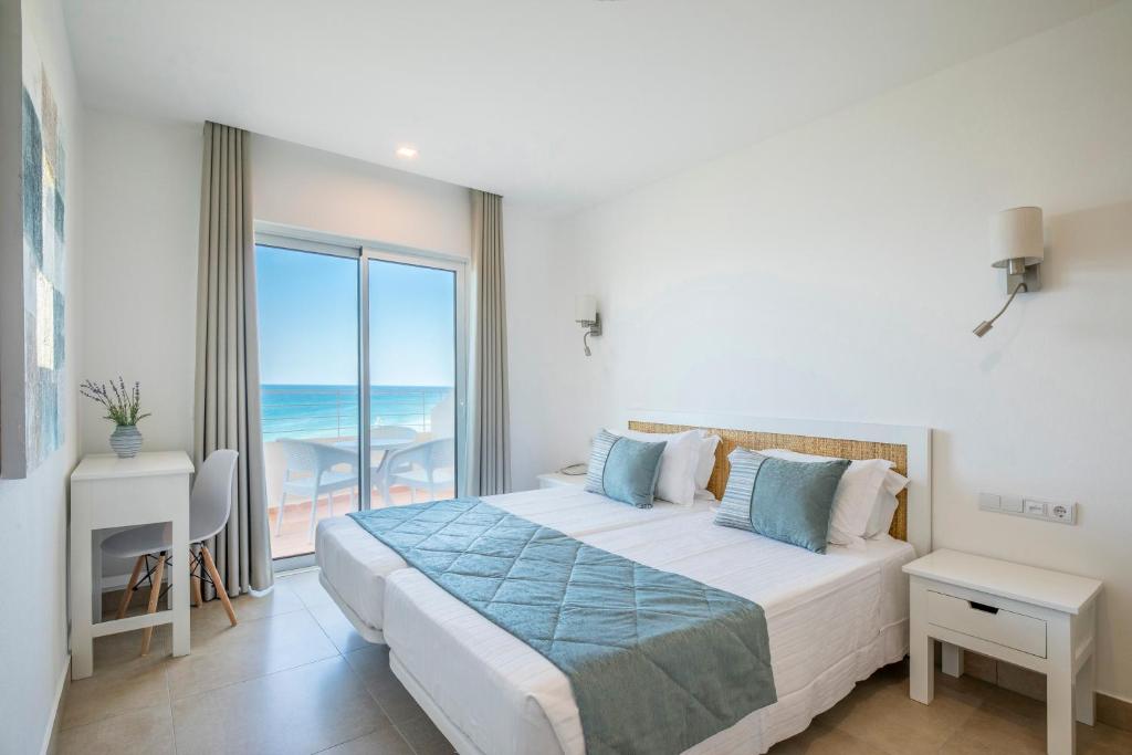 a bedroom with a bed with a view of the ocean at Clube Porto Mos - Sunplace Hotels & Beach Resort in Lagos