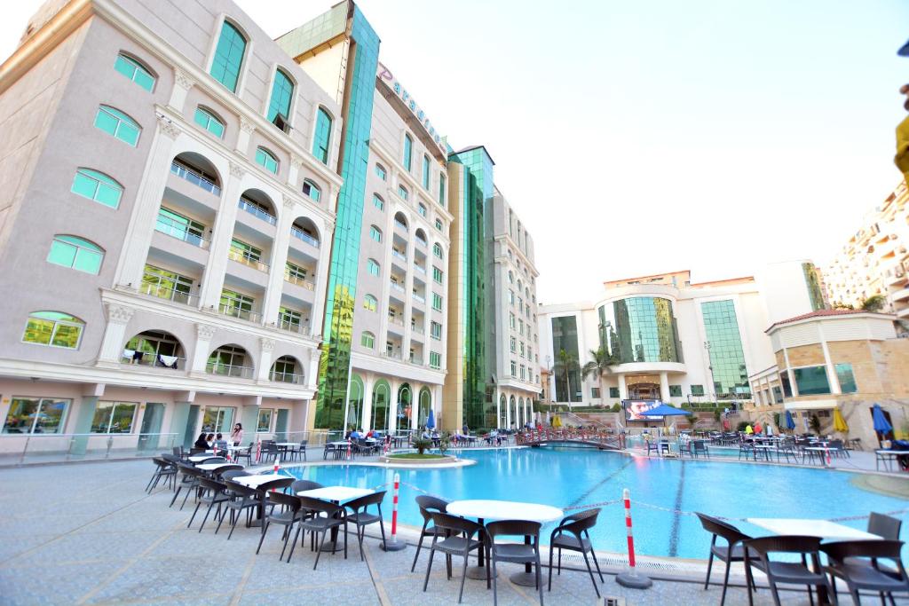 een groot zwembad met tafels en stoelen in een stad bij Paradise Home City Stars in Caïro
