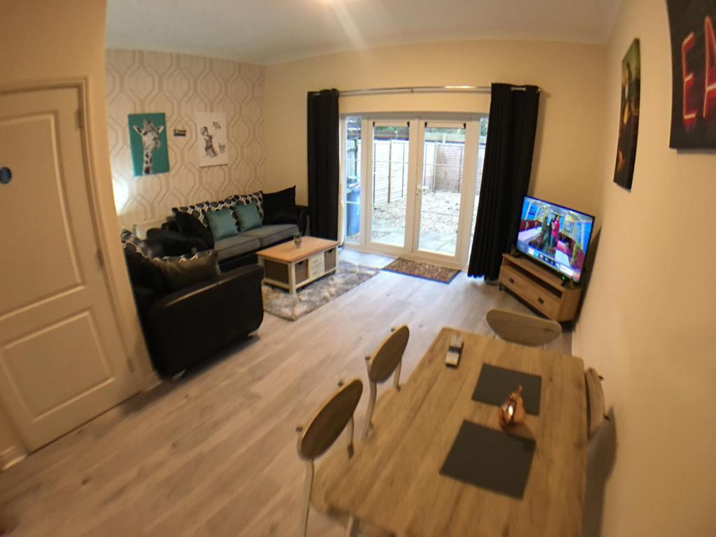 波士顿Very LARGE House, 6 beds, 4 bedrooms, 3 Bathrooms, 5 Smart TV's & VAN PARKING的带桌子和沙发的客厅