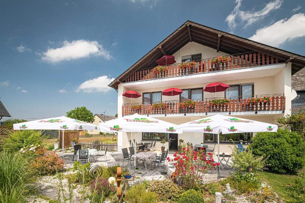 a building with tables and umbrellas in front of it at Landhaus Heimisch Bed & Breakfast in Geisfeld