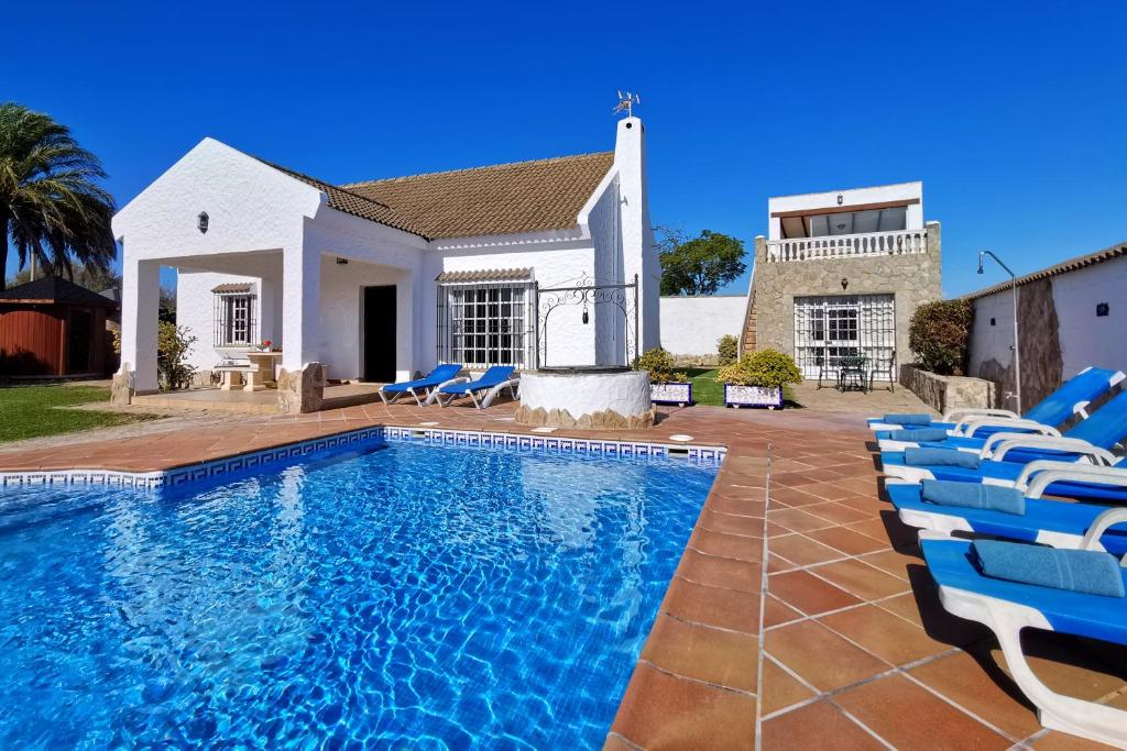 una casa con una piscina con sillas azules en Casa Zahora, en Zahora