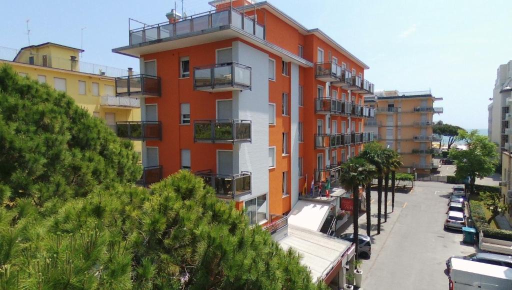 un bâtiment orange et blanc dans une rue de la ville dans l'établissement Hotel Torino, à Lido di Jesolo