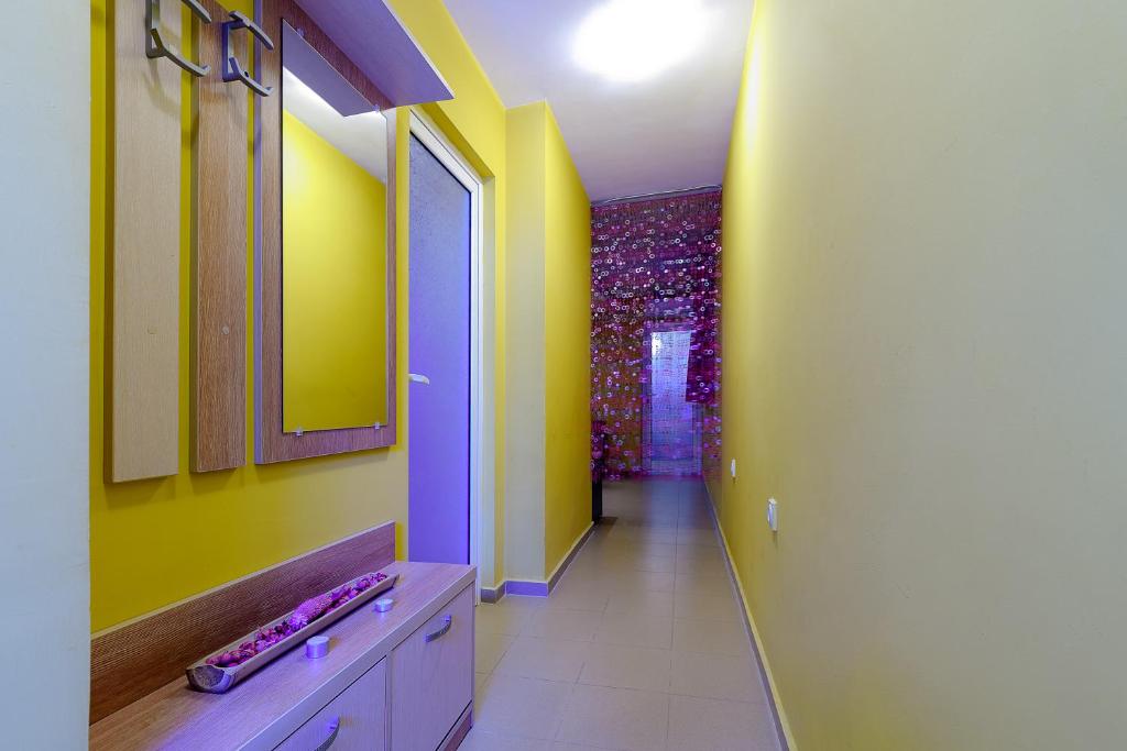 a bathroom with yellow and green walls and a hallway at Evridika Apartments in Nesebar