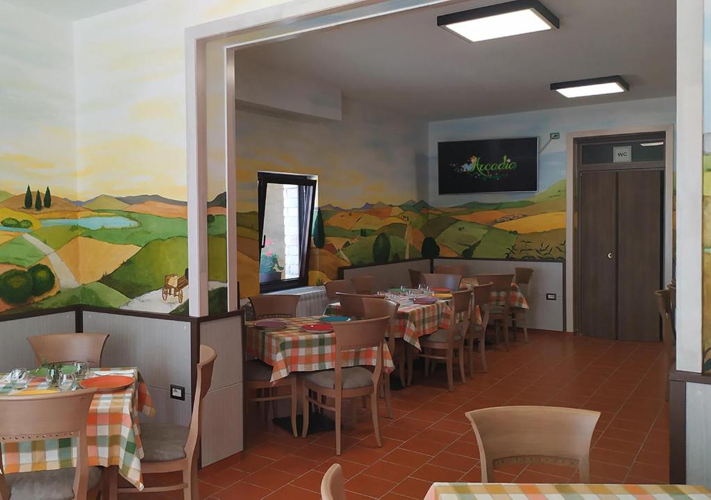Locanda Arcadia في Picerno: مطعم بطاولات وكراسي و لوحة على الحائط