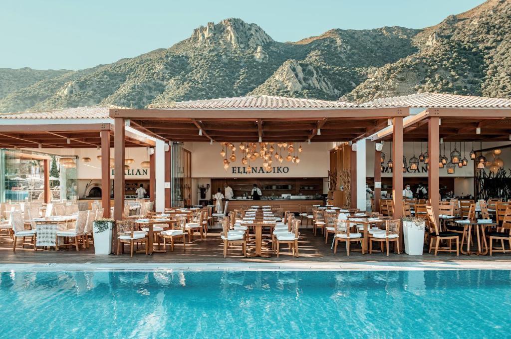 a restaurant with a swimming pool next to a mountain at Mitsis Selection Blue Domes in Kardamaina