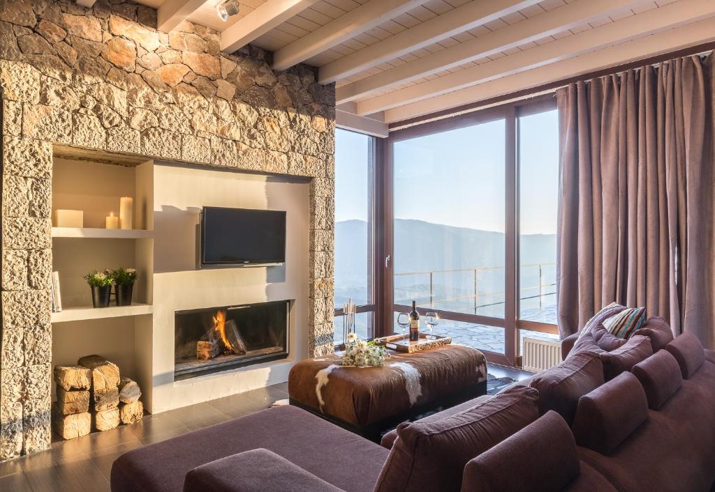 a living room with a stone wall and a fireplace at White Hills Villas in Arachova