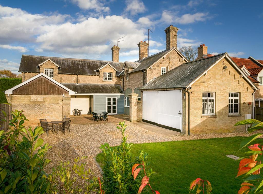 a large brick house with a garage and a yard at Finest Retreats - The Stables at Crimplesham in Stradsett