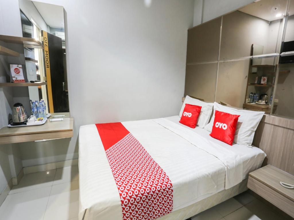 una camera da letto con un grande letto con cuscini rossi di SUPER OYO Capital O 90056 Wisma Kebon Kacang 9 a Giacarta