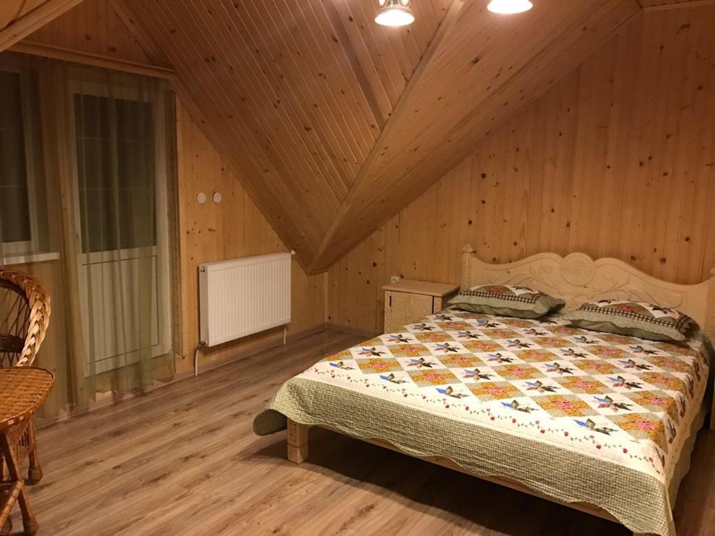 ein Schlafzimmer mit einem Bett in einem Holzzimmer in der Unterkunft Писанка Плюс in Jaremtsche