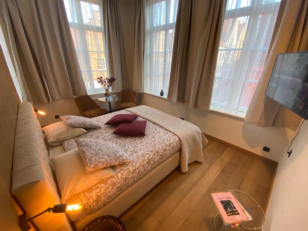 a bedroom with a bed and a couch and windows at B&B Augusto in Bruges