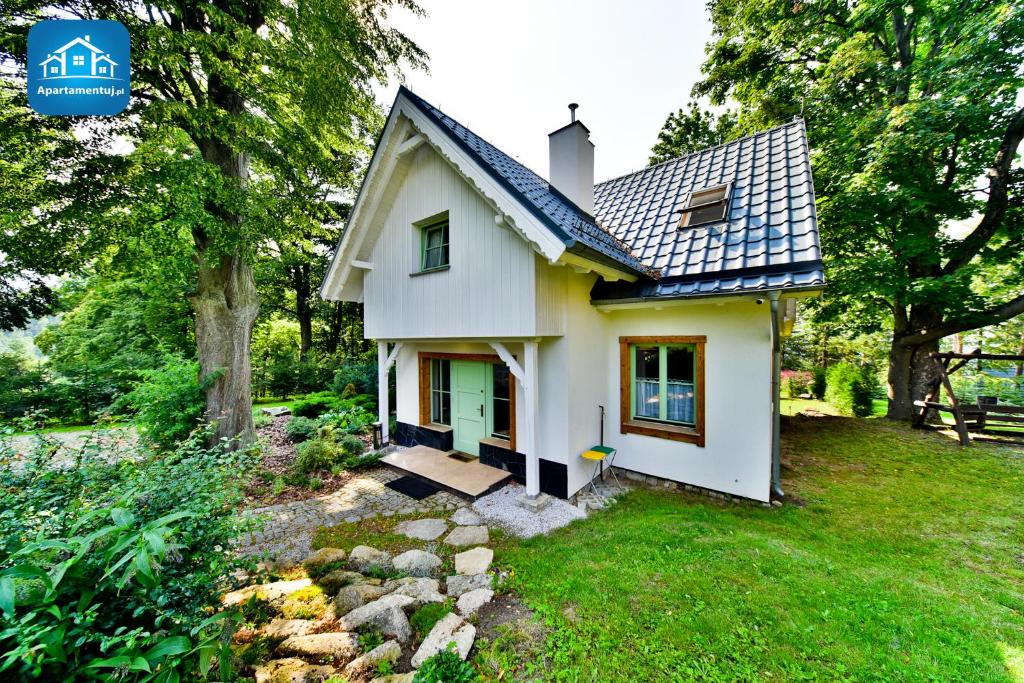 una piccola casa bianca con una porta verde di Michałowy Domek koło Karpacza - Apartamentuj a Karpacz