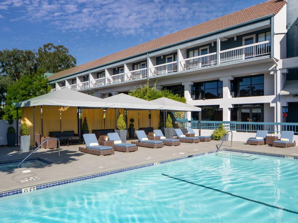un hotel con piscina, sillas y un edificio en The Domain Hotel, en Sunnyvale
