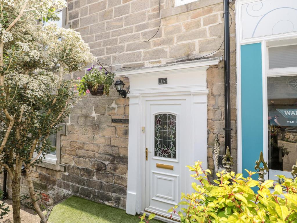 uma porta branca da frente de uma casa com uma parede de tijolos em 1A Chantry Place em Morpeth