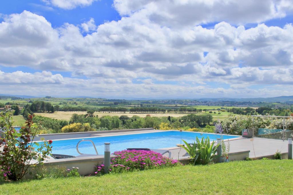 a large swimming pool in a yard with flowers at B&B-Les Balcons de Maragon in Carcassonne