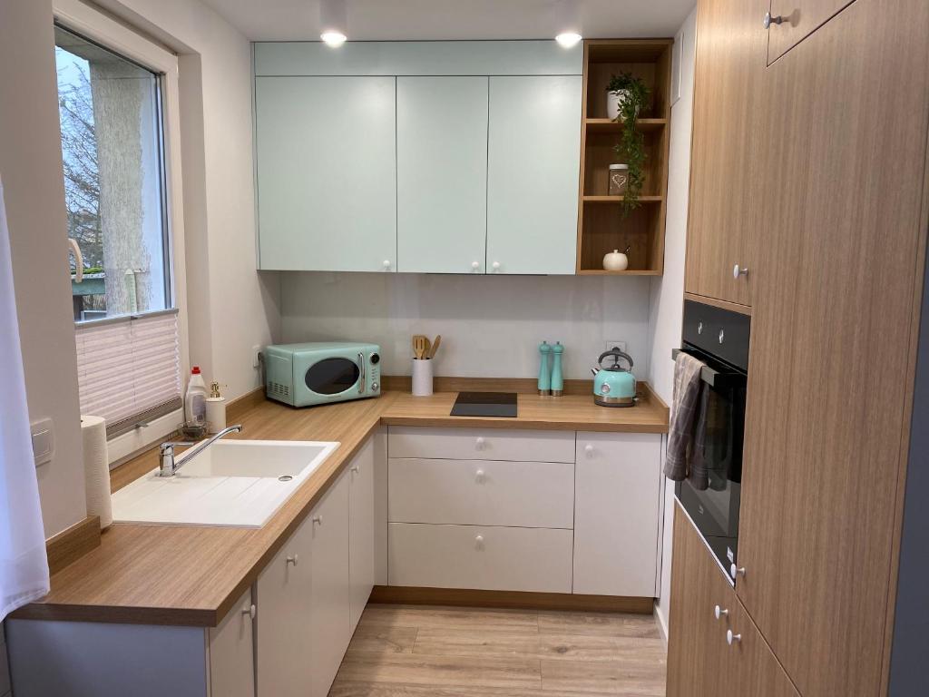 a kitchen with white cabinets and a sink and a microwave at Apartament uTymka in Słupsk