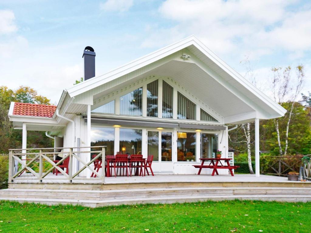 una casa blanca con mesas de picnic rojas en una terraza en 6 person holiday home in BRASTAD, en Brastad