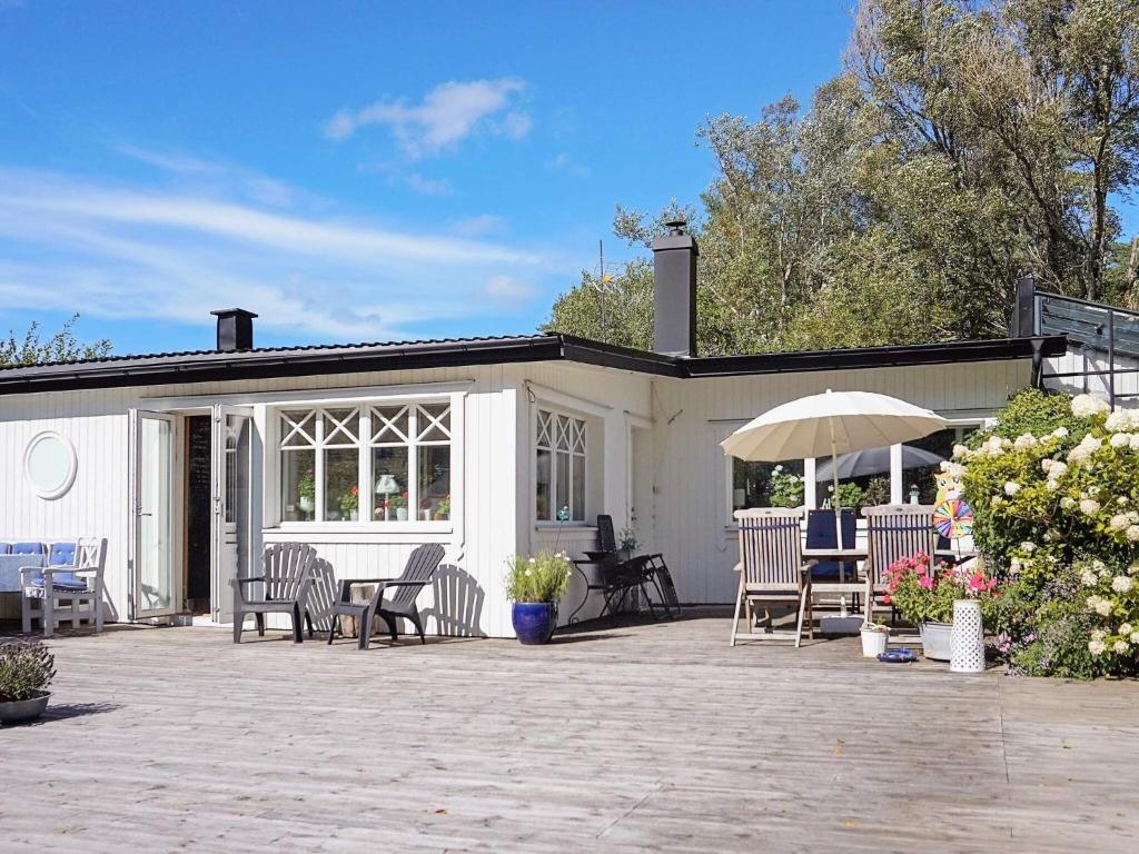 eine Terrasse mit Stühlen, Tischen und einem Sonnenschirm in der Unterkunft 8 person holiday home in FAGERFJ LL R NN NG in Bräcke