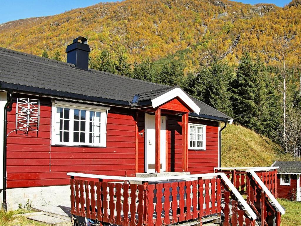 ein rotes Haus mit einer Holzterrasse vor einem Berg in der Unterkunft One-Bedroom Holiday home in Øvre Årdal in Øvre Årdal