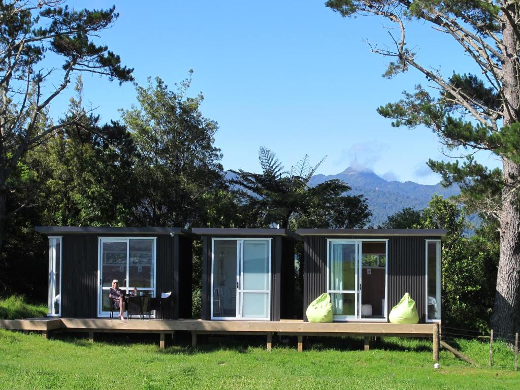 une petite maison noire avec une personne assise sur une terrasse dans l'établissement Waihi Gold Alpacas 3 or 4 people, à Waihi