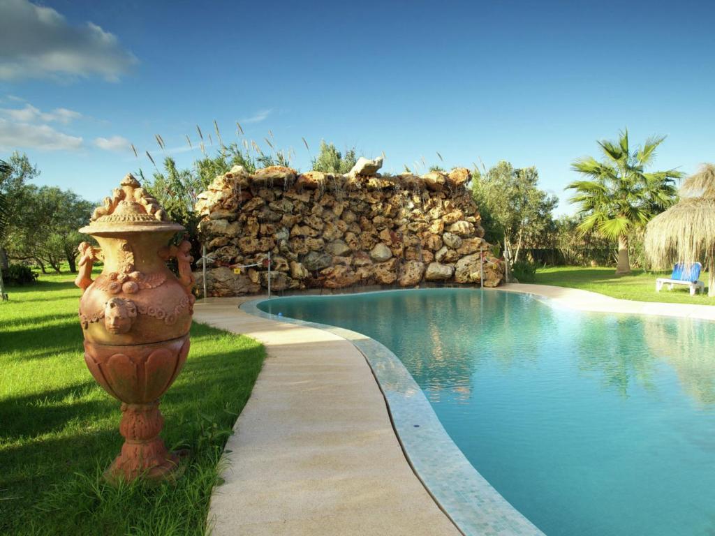 a pool with a fire hydrant next to a stone wall at Belvilla by OYO Gamundi in Muro