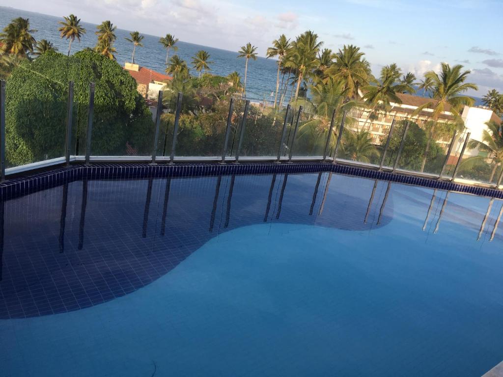 een groot blauw zwembad met uitzicht op de oceaan bij Makaiba Residence in Porto De Galinhas