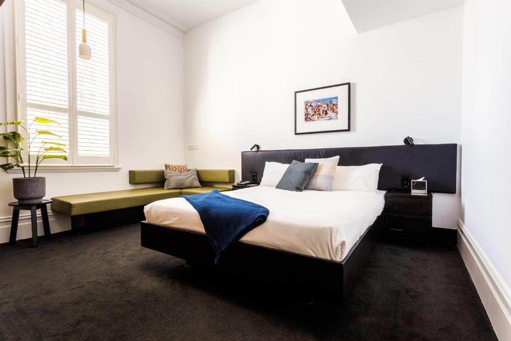 a bedroom with a large bed and a bench at Middle Park Hotel in Melbourne