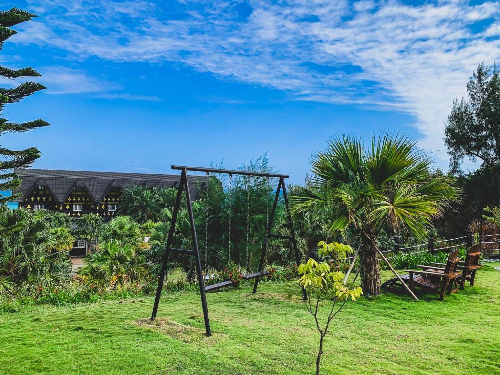 a swing set in a field with a house in the background at Tudor Dynasty Homestay in Yanliau