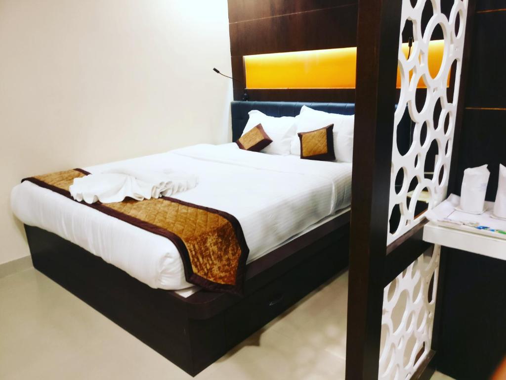 a bedroom with a bed with white sheets and pillows at Citi Inn in Patna