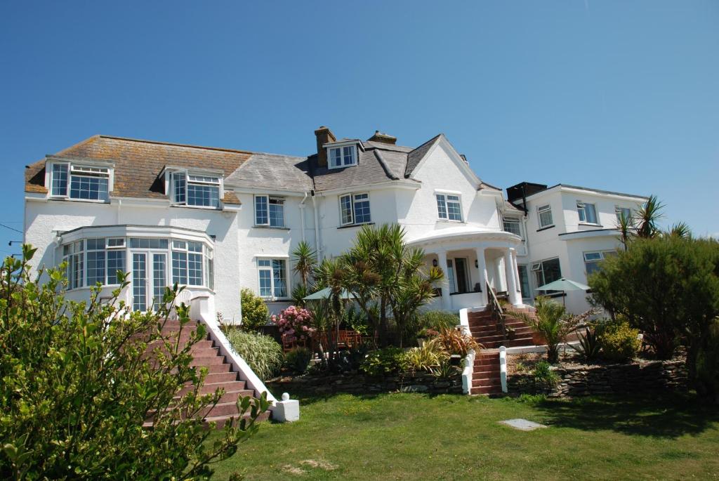 une grande maison blanche avec des escaliers dans une cour dans l'établissement The Whipsiderry Hotel, à Newquay