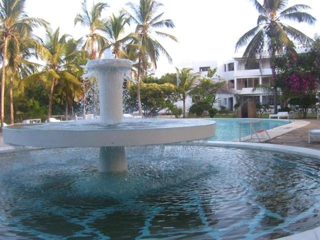 a fountain in the middle of a pool with palm trees at Blue Marlin Sporting Resort in Malindi
