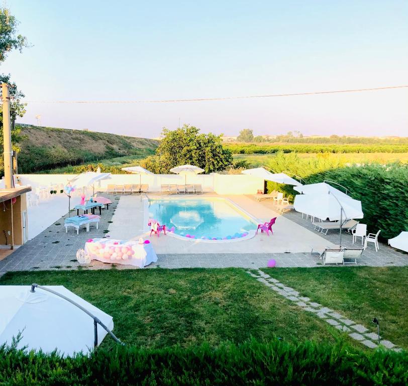 a large swimming pool with tables and chairs in a field at Hotel La Primula in Corigliano Calabro