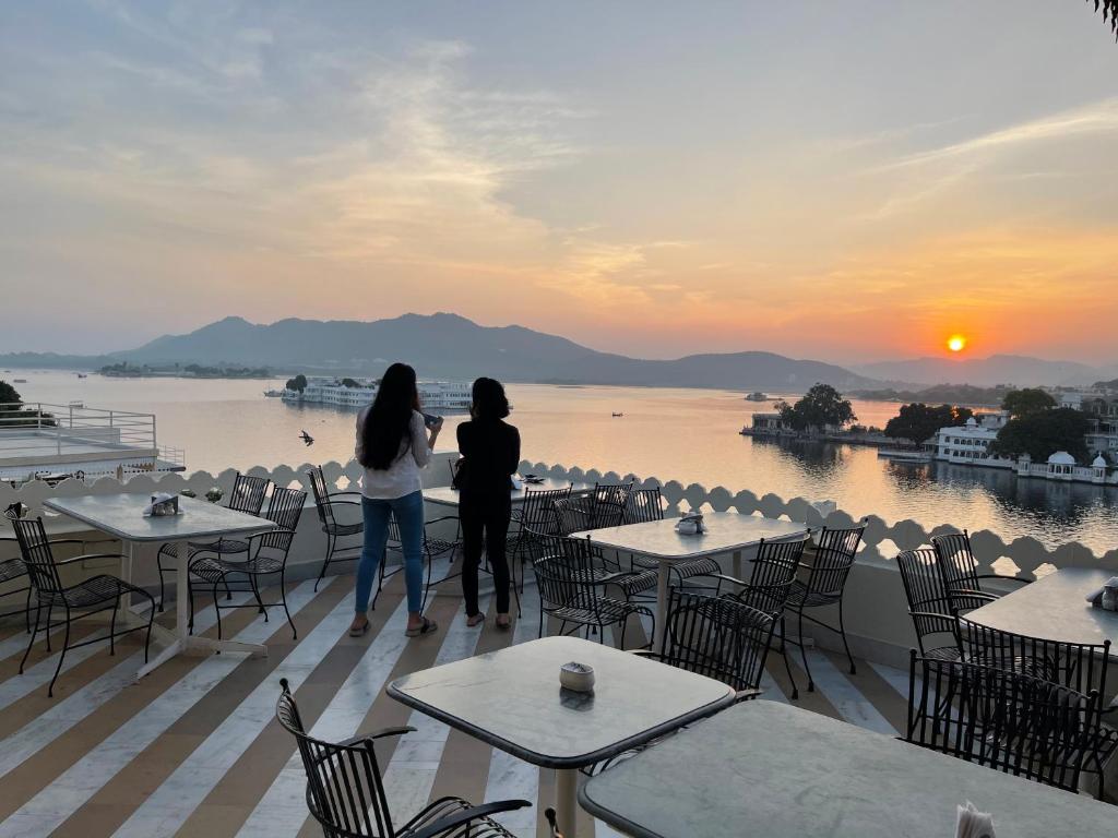 dos mujeres de pie en una cubierta mirando el agua en Jaiwana Haveli, en Udaipur