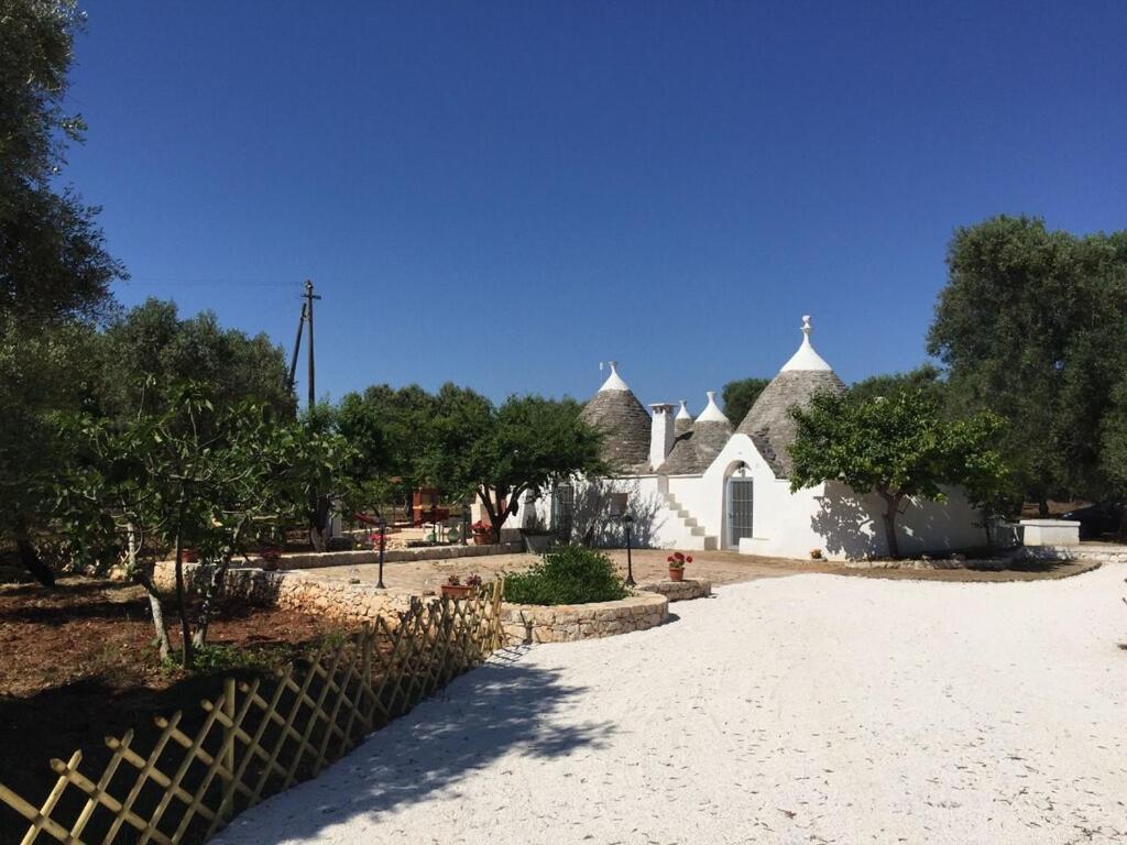 une maison blanche avec une clôture et des arbres dans l'établissement Chateaux des Trulli, à San Michele Salentino