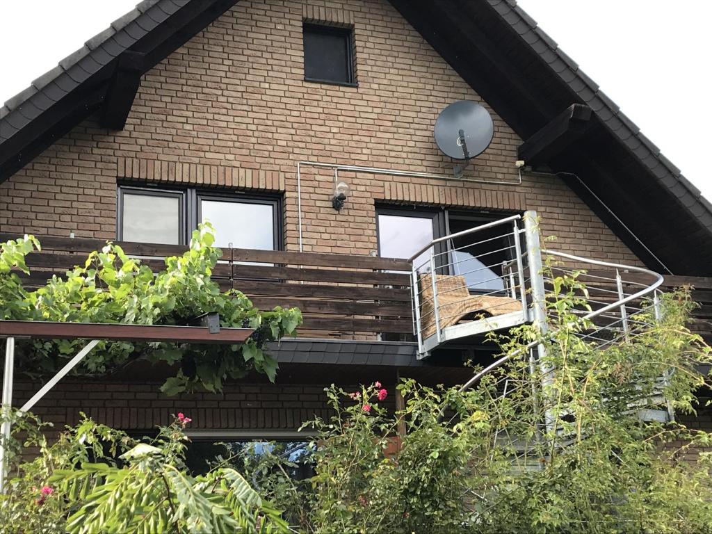 a house with a wooden porch with a stair case at Schöne Ferienwohnung in Kürten in Kürten