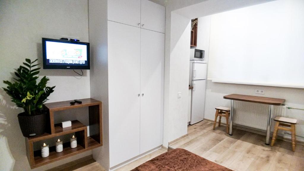 ein Wohnzimmer mit einem TV und einem Tisch in der Unterkunft Белая студия на Южном вокзале in Kharkov