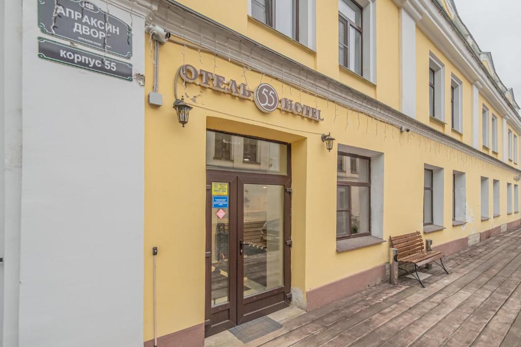 um edifício amarelo com um banco à frente em Hotel 55 em São Petersburgo