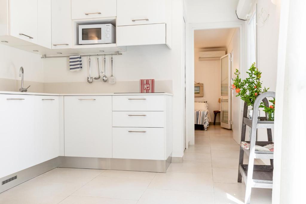 a kitchen with white cabinets and a tv on the wall at Pochi Passi dal Mare in San Bartolomeo al Mare