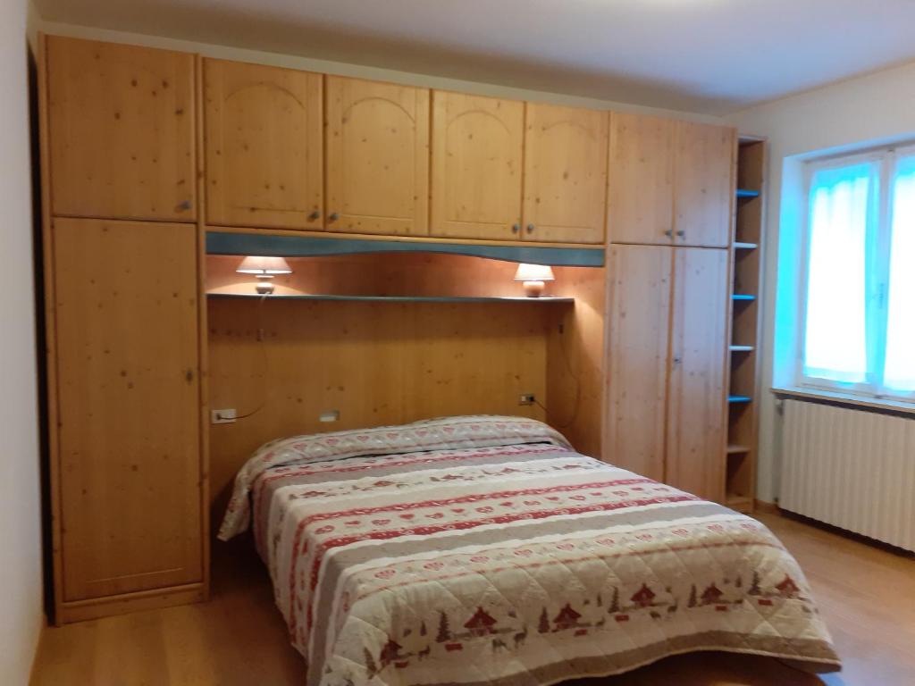 Schlafzimmer mit einem Bett mit einem Kopfteil aus Holz in der Unterkunft Vacanzemoena - Casa al Parco, tipologia 2 in Moena