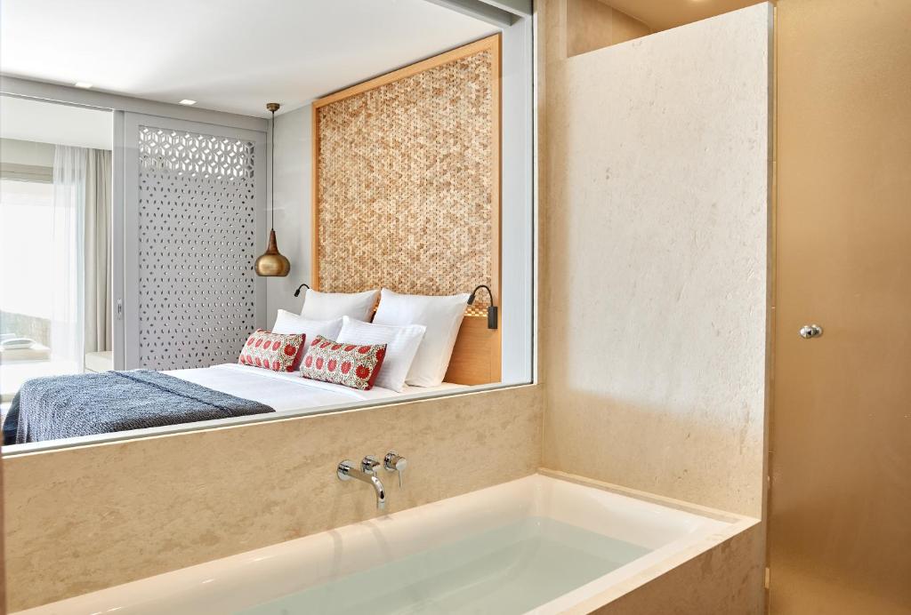 a bathroom with a bed and a tub in a room at Elix, Mar-Bella Collection in Perdika