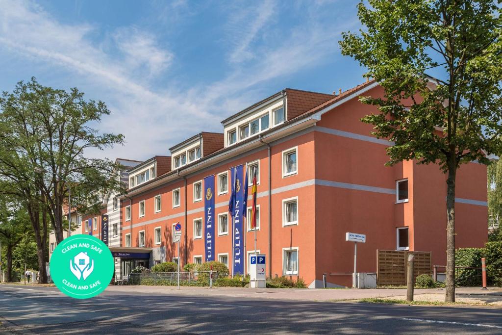 een gebouw met een groen bord ervoor bij Tulip Inn Frankfurt Airport in Neu Isenburg