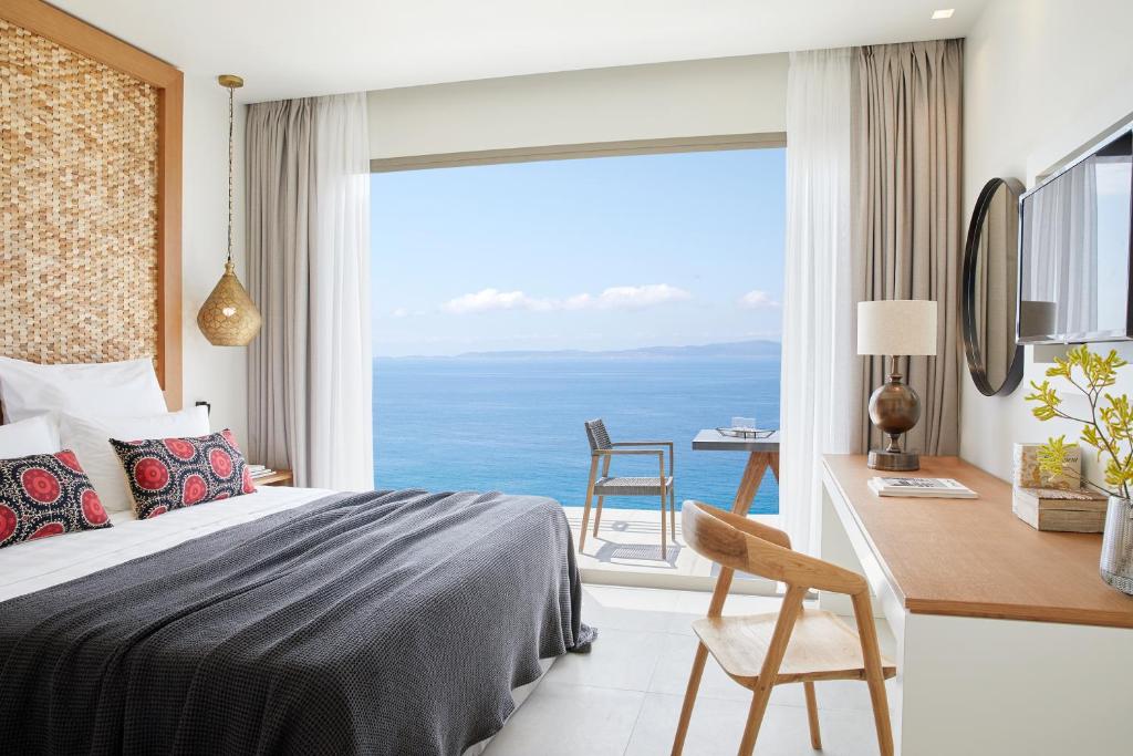 a bedroom with a bed and a desk with a view at Elix, Mar-Bella Collection in Perdika