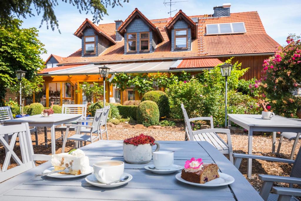 a table with cakes and cups on it in front of a house at Blütenhotel Village in Sarnau