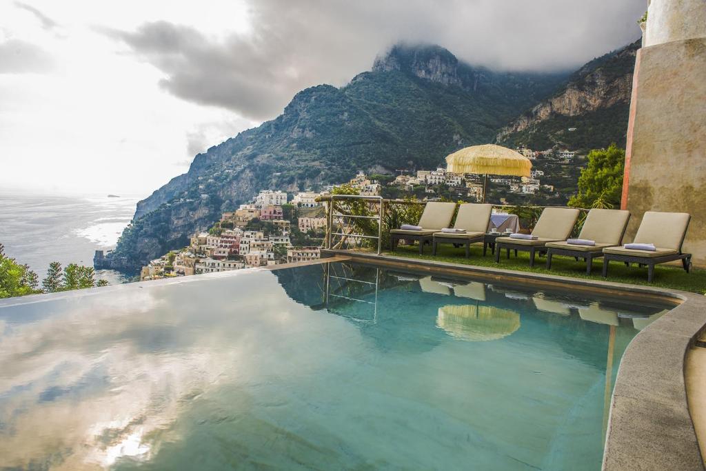 a pool with chairs and a view of a city at Amore Rentals - Villa Angelina in Positano