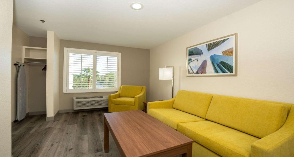 a living room with a yellow couch and a table at Best Western Houston Bush IAH Intercontinental Airport Inn in Humble