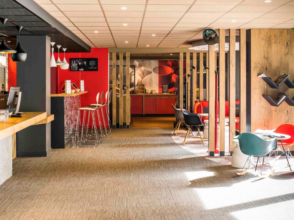 un restaurant avec des murs et des chaises rouges et un bar dans l'établissement ibis Paris Pont de Suresnes Longchamp, à Suresnes