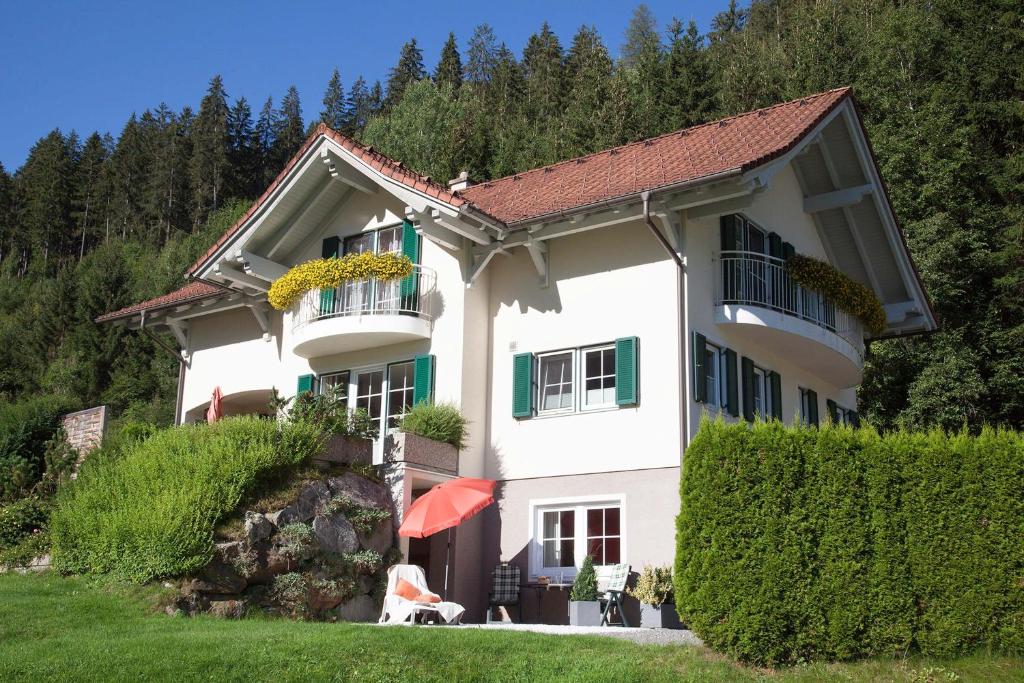 een wit huis met groene ramen en een heg bij Chalet Claudia in Neustift im Stubaital