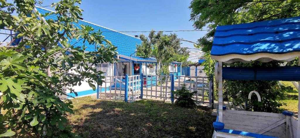 un parque infantil con una valla azul frente a una casa en Sailors Guest House Jurilovca en Jurilovca