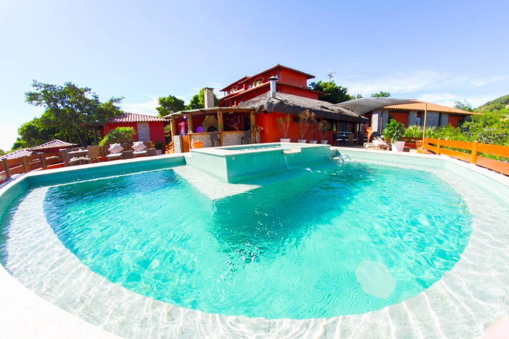 uma grande piscina com água azul em frente a uma casa em Azeda Boutique Hotel em Búzios